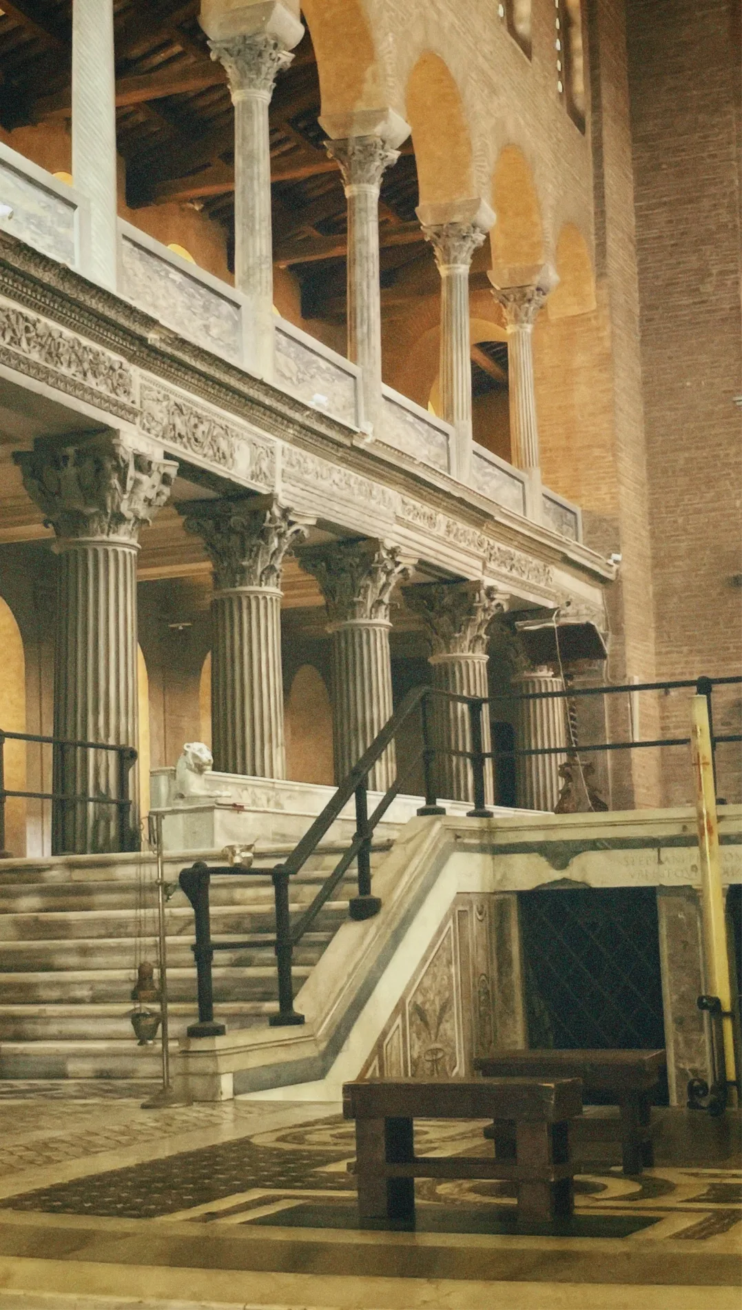 Marble steps and fluted columns of a Roman basilica, with an arcaded gallery above